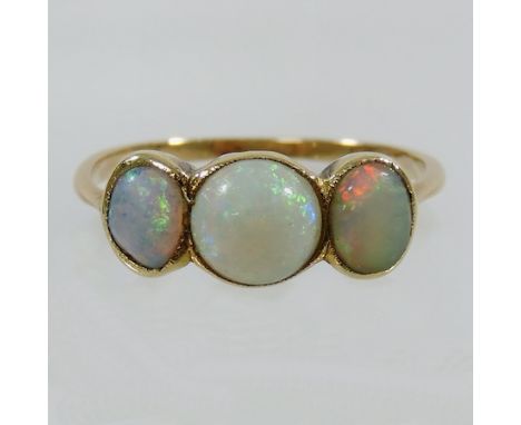 An unmarked yellow metal three stone opal ring