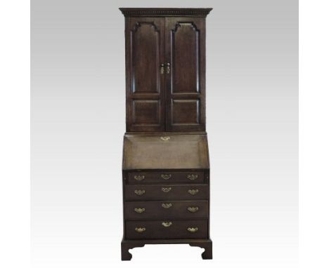 An 18th century style oak bureau cabinet, of small proportions, enclosed by a pair of panelled doors, above a hinged fall, on