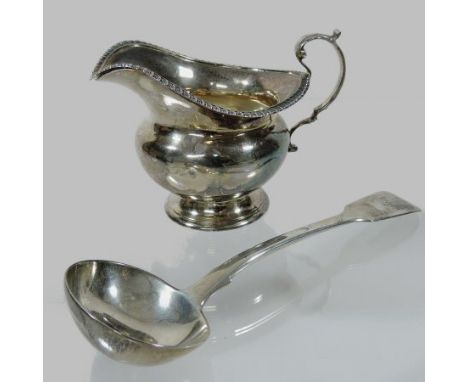 An early 20th century silver helmet shaped cream jug, Chester 1908, 9cm tall, together with a silver ladle, London 1924