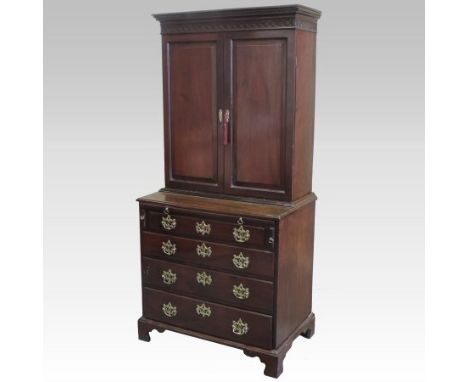 A George III style mahogany cabinet on chest, the upper section fitted with shelves and enclosed by a pair of panelled doors,