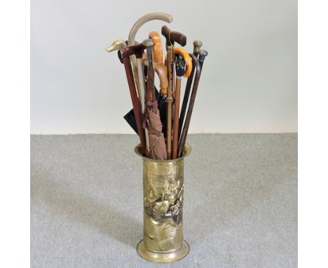 A collection of walking sticks, to include a silver mounted stick, in a brass stand