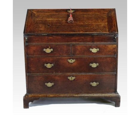 An early 18th century oak bureau, the stepped interior with a well, enclosed by a hinged sloping fall, with drawers below, on