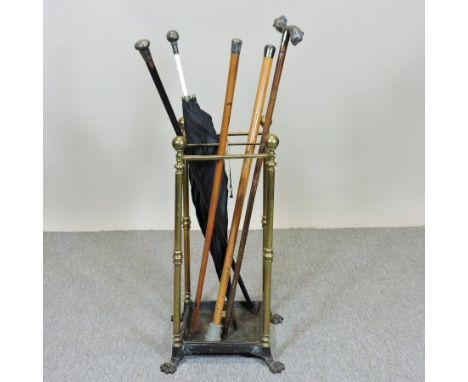 A Victorian brass stick stand, on paw feet, containing an early 20th century umbrella, with a silver mounted ivory handle, th