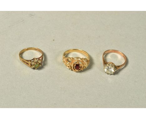 THREE 9CT GOLD GEM SET RINGS, the first set with a colourless circular cubic zirconia, the second a floral paste cluster, the