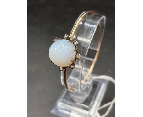 A GOOD QUALITY GOLD HIGH CARAT BANGLE WITH LARGE CHALCEDONY/MOONSTONE SURROUNDED BY 8 GOOD CLEAR DIAMONDS