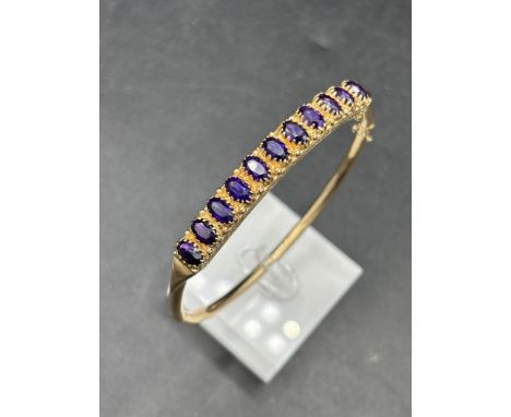A PRETTY ELEVEN STONE OVAL AMETHYST HINGED BANGLE SET IN 9CT 11 GMS