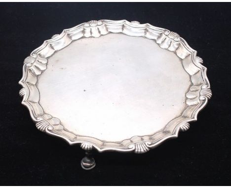 A George II silver salver, raised border with shell and scroll rim, plain centre, on three hoof feet, engraved initials: C ab