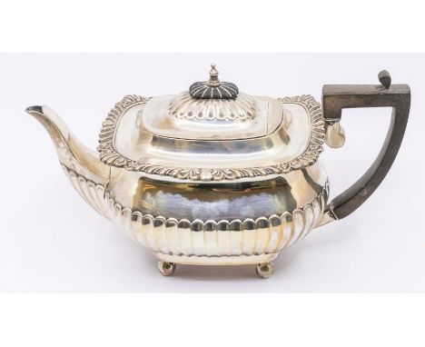 A Georgian style silver teapot, with gadroon and scroll cast apron, the body fluted lower section on four ball feet, the cove