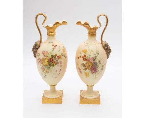 A pair of early 20th century Royal Worcester blush ivory handled ewers on square bases with flower, Bacchus and gilt detail, 