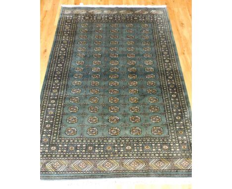 Bokhara design carpet, decorated with five rows of elephant pad medallions to centre over olive green ground, within reticula