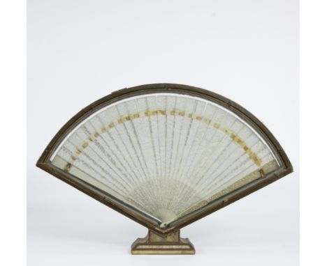 Elegant hand fan made of finely carved bone with floral motifs, in a semi-circular wooden display case on a pedestal, probabl