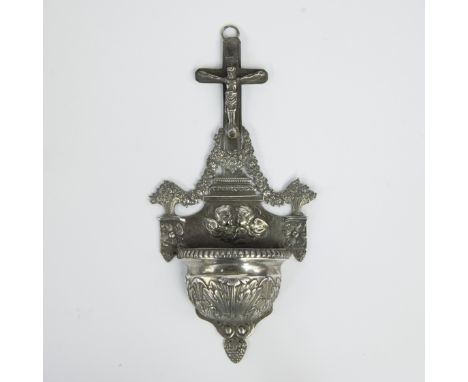 Richly decorated silver holy water font crowned with a crucifix and Corpus Christi and lavishly decorated with garlands, styl