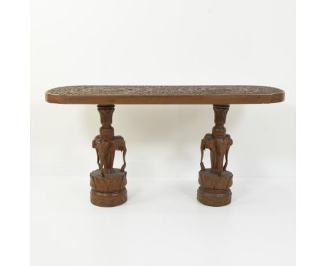 Wooden table with engraved top and two legs, each supported by three carved elephants on round plinths, South Asia, 20th cent