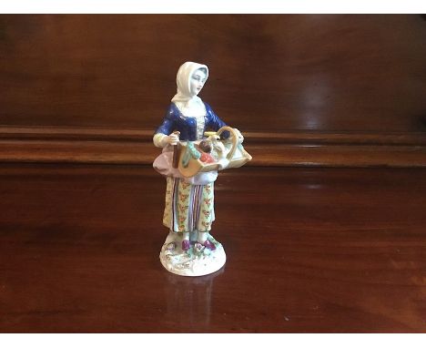 A Naples figure of a Lady holding a basket with a baby in.Date early 19ty century. Crown and N.Size 16cm. high.Condition; Lef