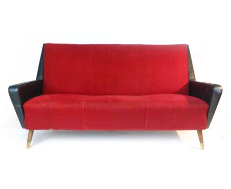 A 1950's G-Plan black vinyl and red upholstered three seater sofa on teak tapering feet terminating with brass castors