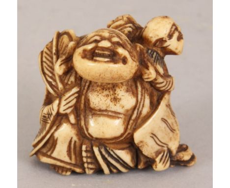 AN 18TH/19TH CENTURY JAPANESE STAGHORN NETSUKE OF HOTEI, holding a fan and in the company of a boy bearing a scroll, 1.8in wi