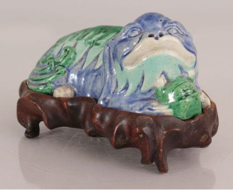 AN UNUSUAL 19TH/20TH CENTURY CHINESE PORCELAIN MODEL OF A RESTING BUDDHISTIC LION, clasping a mask between its paws, together