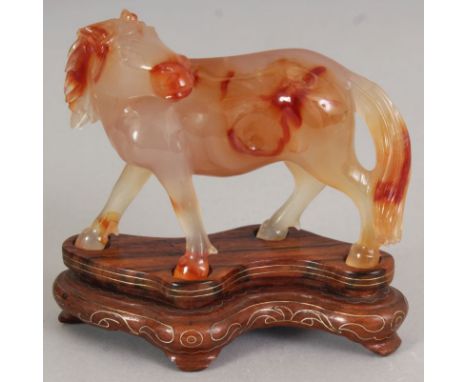 A CHINESE AGATE MODEL OF A STANDING HORSE, its head turned backwards, together with a wire-inlaid wood stand, the carving its