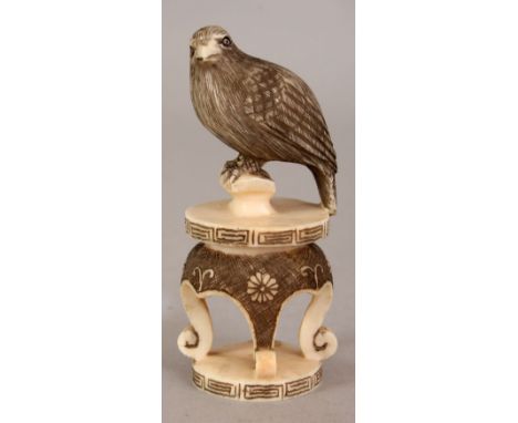 AN EARLY 20TH CENTURY SIGNED JAPANESE IVORY NETSUKE OF A HAWK, perched on a scroll-footed stand, the details engraved and sta