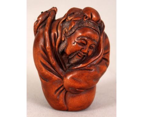 A 20TH CENTURY SIGNED JAPANESE WOOD NETSUKE OF A FISHERMAN SAGE, with enveloping robes and holding two carp from a bamboo pol