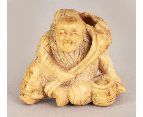 A JAPANESE MEIJI PERIOD STAGHORN NETSUKE OF A SEATED MAN, bearing a leafy frond, 1.9in wide at widest point & 1.6in high.