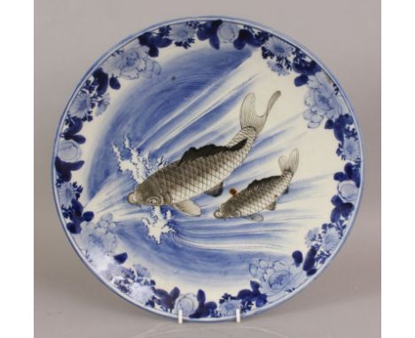 AN EARLY 20TH CENTURY JAPANESE BLUE & WHITE PORCELAIN DISH, painted in black enamel with a pair of swimming carp, 12in diamet