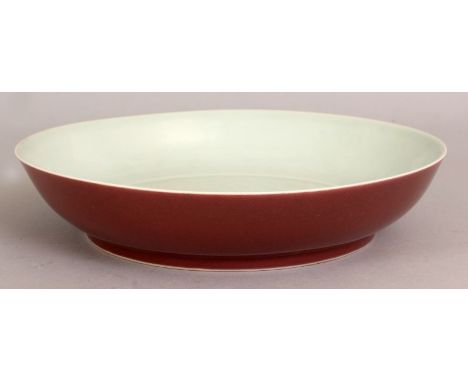 A CHINESE PORCELAIN DISH, of saucer shape, the exterior sides applied with a copper red glaze, the interior incised beneath t