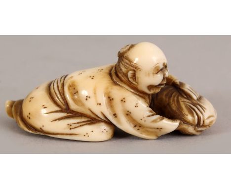 A JAPANESE MEIJI PERIOD IVORY NETSUKE OF A MAN HOLDING DOWN A LARGE CARP, 2in long.