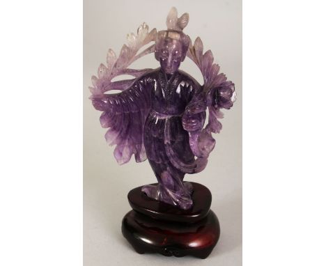 ANOTHER CHINESE AMETHYST FIGURE OF GUANYIN, together with a fitted wood stand, the Goddess holding a floral spay and a wreath
