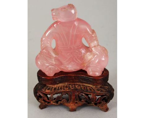 A SMALL CHINESE ROSE QUARTZ MODEL OF A SQUATTING MONKEY GOD, together with a fitted wood stand, 3.25in high overall, the carv