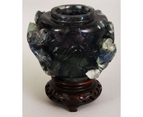 AN UNUSUAL CHINESE QUARTZ VASE, together with a wood stand, the vase carved to its side in high relief with buddhistic lions,