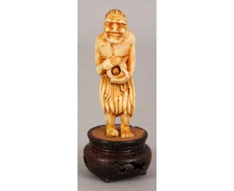 AN UNUSUAL JAPANESE MEIJI PERIOD IVORY NETSUKE OF AN EMACIATED SENNIN, together with a fixed wood stand, the sage with a reed