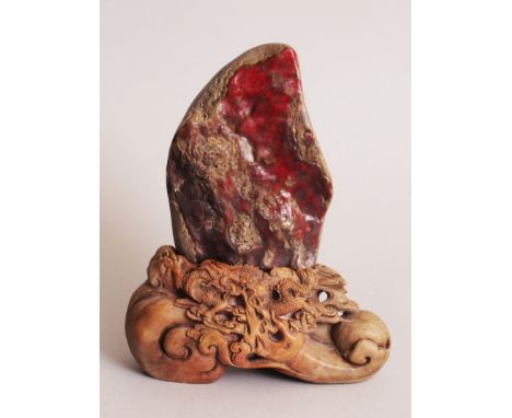 A CHINESE CHICKEN BLOOD STONE STYLE BOULDER CARVING, together with a fitted soapstone style stand, 9.3in high overall, the st