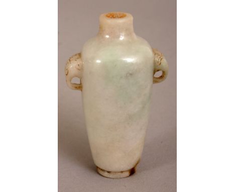 A CHINESE JADE SNUFF BOTTLE, the predominantly pale celadon stone with brown inclusions, the sides with double animal mask ha