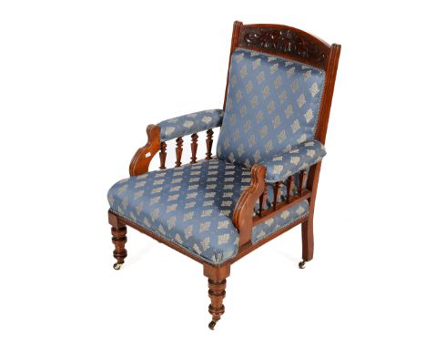 A late Victorian upholstered library arm chair. Walnut framed with carved details to back raised on small brass and ceramic c