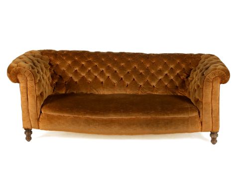 A Victorian Chesterfield sofa. Upholstered in brown velvet with scroll arms and a button back, raised on turned mahogany supp