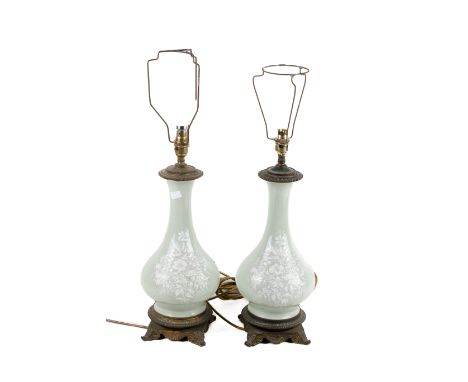 A pair of 19th century bronze and porcelain lamps. The lamps glazed in green celadon and featuring pâte-sur-pâte relief decor