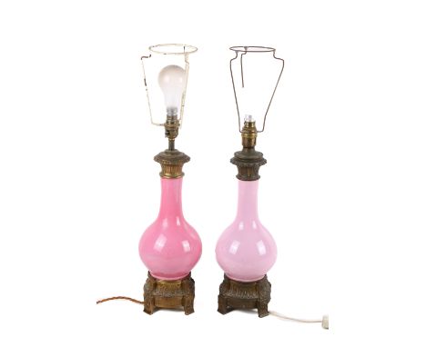A near pair of 20th century pink ceramic lamp bases. The bulbous stands topped with a brass collar, mounted on a brass base w