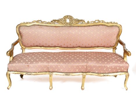 An early 20th century, Loius XV style giltwood and gesso salon sofa and chair. With carved decoration and serpentine front la