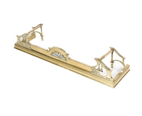 An Edwardian brass fire fender. Having pierced and scroll decoration with attached dogs raised on a moulded plinth. H23cm x W