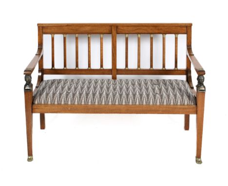 An early 20th century French Empire style oak two seater sofa. The back panel with turned supports with brass fittings, brass