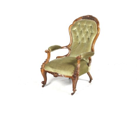 A Victorian spoon-back open armchair. The mahogany frame carved with scrolls and floral decoration, the button back seat and 