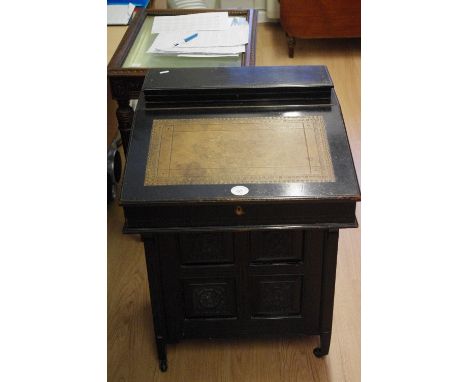 An Edwardian ebonised davenport with raised stationery box compartment, with slope inset with tooled leather, enclosing two s