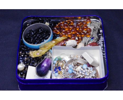 A Cadbury's tin with an assortment of costume jewellery including a silver bangle, beads, a Mussel scent bottle, etc.