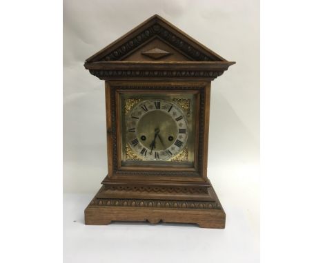 An oak mantle clock the silver coloured dial with Roman numerals