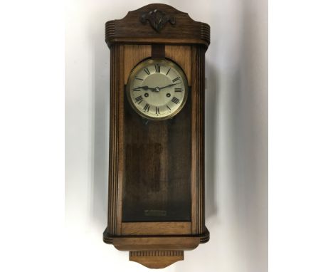 An 8 day oak cased wall clock with key and pendulum.