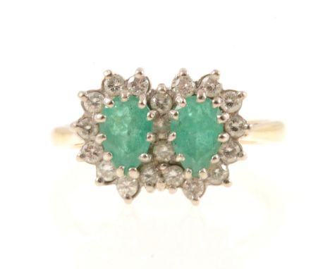 An emerald and diamond cluster ring, two pear shaped emeralds surrounded by twenty brilliant cut diamonds in an 18 carat yell