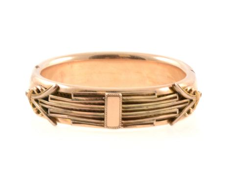 An Edwardian yellow metal hinged bangle, unmarked, with applied decoration, 62mm internal diameter.