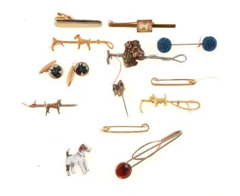 A 1950s gilt metal tie slide with terrier motif, 70mm; a metal tie pin in the form of a riding crop, with mounted ivorine Sco