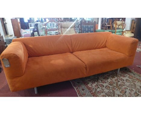 A contemporary three seater sofa having orange Alcantara removable covers and raised on steel legs. 